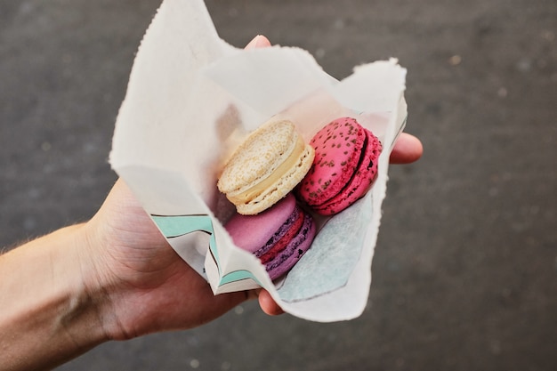 Hände, die bunte Pastellkuchen macarons oder Makronen in der Tasche halten