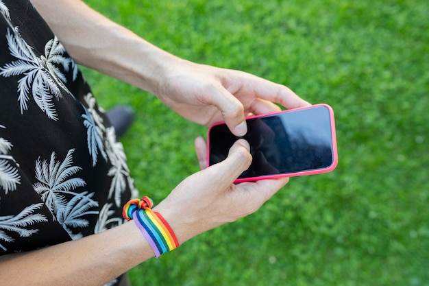 Hände, die ein Handy benutzen, tragen ein LGBT-Armband