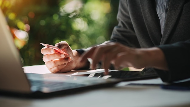 Hände, die eine Kreditkarte halten und einen Laptop zum Online-Shopping verwenden