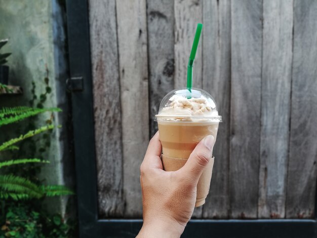 Hände, die eine Schale kalten Kaffee anhalten.