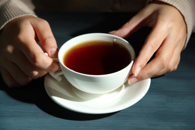 Hände, die eine Tasse heißes Getränk in der Nähe halten