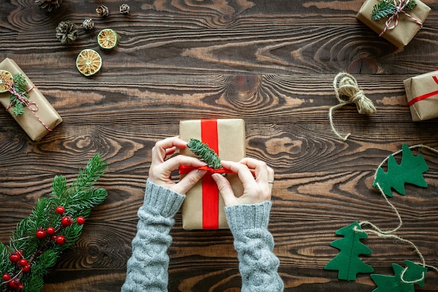 Hände, die eine Weihnachtsgeschenkbox verzieren