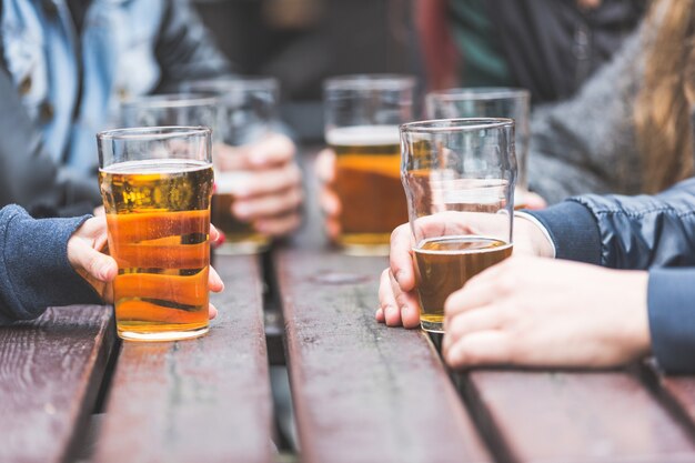 Hände, die Gläser mit Bier auf einer Tabelle in London halten