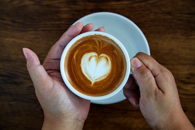 Hände, die Kaffeetasse-Herzschale halten