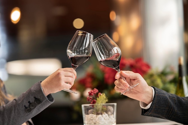 Hände, die mit einem Glas Wein anstoßen, um das neue Jahr zu feiern