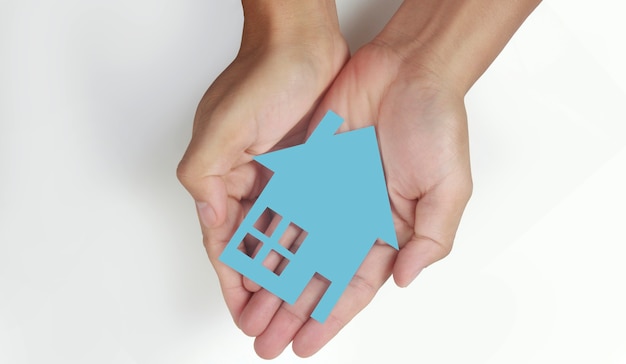 Hände, die Papierhaus, Einfamilienhaus halten und Versicherungskonzept schützen