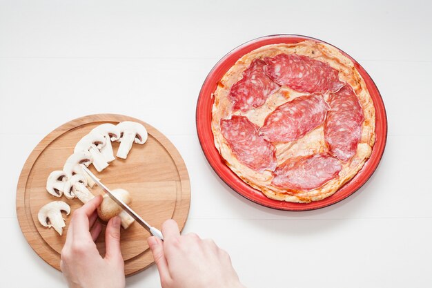 Foto hände, die pilze für pizza schneiden