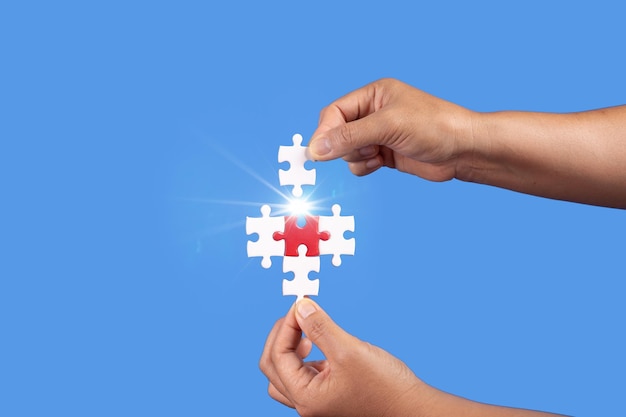 Hände, die Puzzleteile mit klarem blauem Hintergrund halten Erfolg Geschäftslösung Strategie Teamarbeit Partnerschaftskonzept