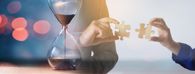 Hände, die Puzzleteile mit Uhr setzen