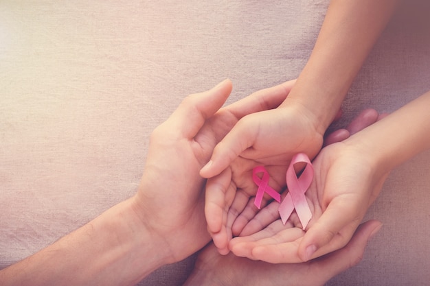 Hände, die rosa Bänder, Brustkrebsbewusstsein halten
