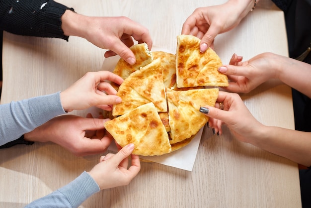 Hände, die Scheiben Tortilla mit Hüttenkäse oder Vertuta von einem Holzteller nehmen, Nahaufnahme