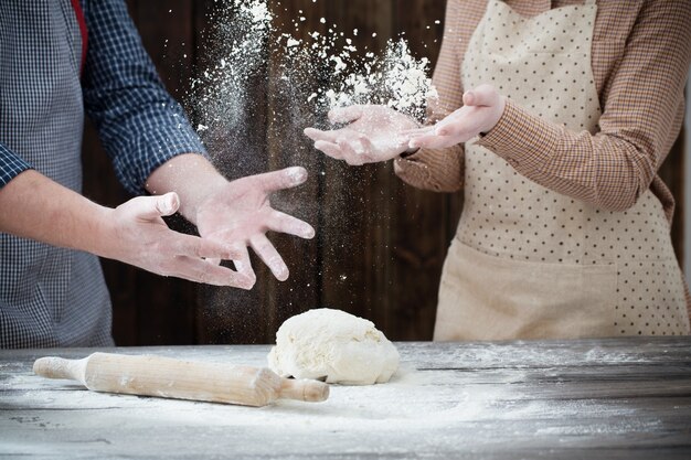 Hände, die Teig auf dunklem Holz kochen