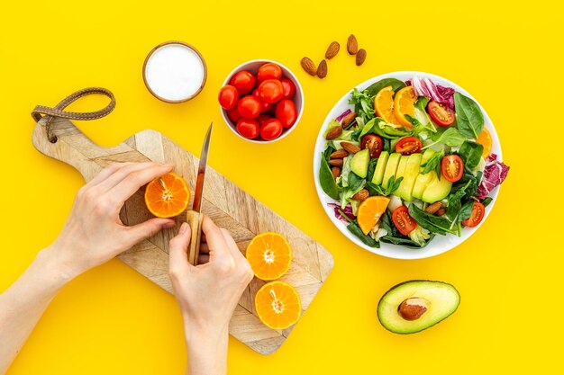 Hände, die vegetarischen Salat mit Avocado und Tomaten kochen