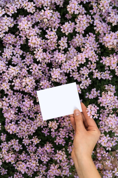 Hände, die vertikale Karte mit Blumen halten