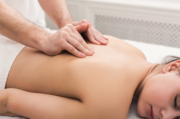 Hände, die weiblichen Rücken und Schultern massieren. Professionelle Körperbehandlung oder Entspannungsverfahren im Spa-Salon. Gesundheits-, Schönheits- und Wellnesskonzept.