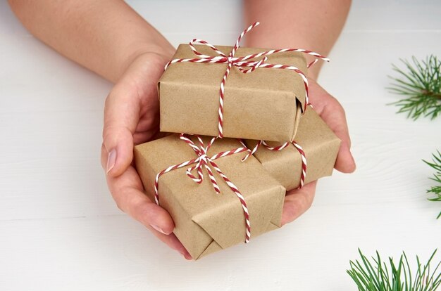 Hände, die Weihnachtsgeschenkboxen über Weiß halten