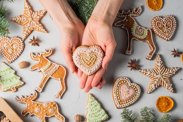 Hände, die Weihnachtslebkuchen halten Festliche hausgemachte verzierte Süßigkeiten