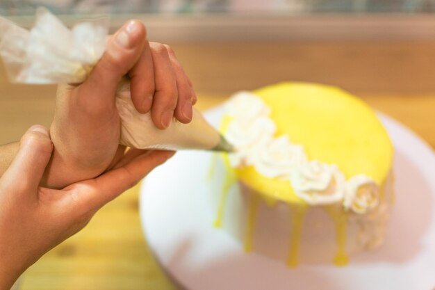 Hände, die Zitronenkuchen dekorieren und zubereiten Das Konzept von hausgemachtem und professionellem Gebäck