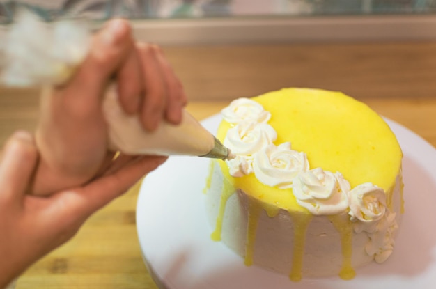 Hände, die Zitronenkuchen dekorieren und zubereiten Das Konzept von hausgemachtem und professionellem Gebäck