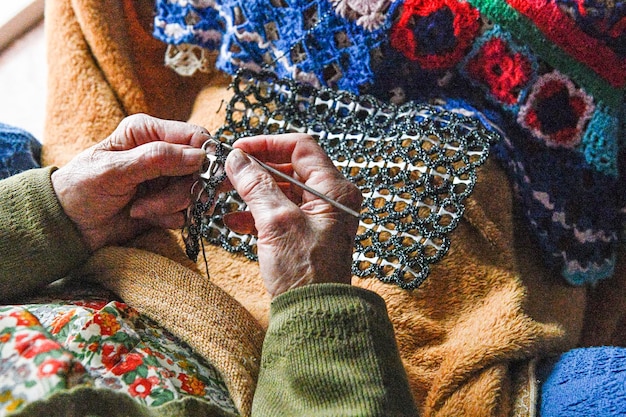 Hände einer älteren Frau, die am Handwerk arbeitet