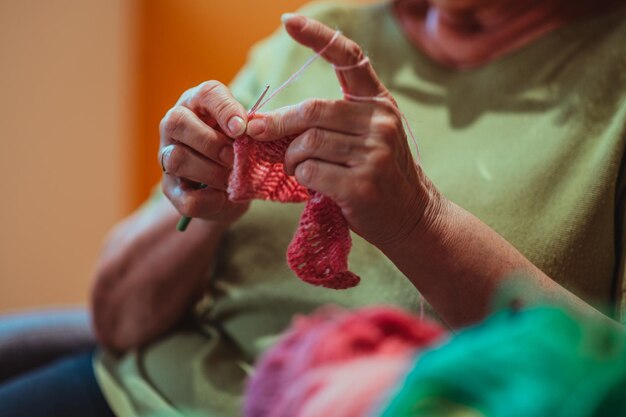 Hände einer älteren Frau, die zu Hause strickt