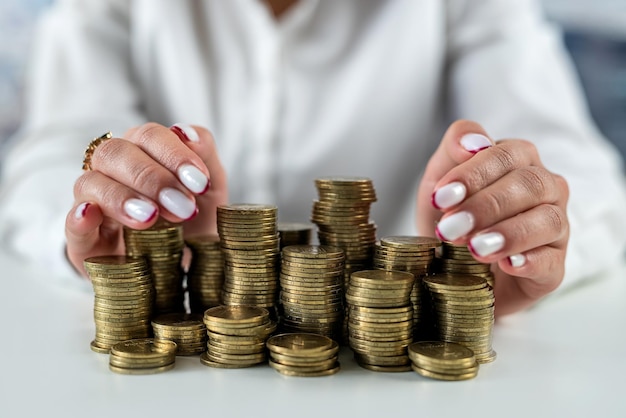 Hände einer Frau auf einem Spiegeltisch mit einer Achterbahn mit Münzen, die Geld umarmen