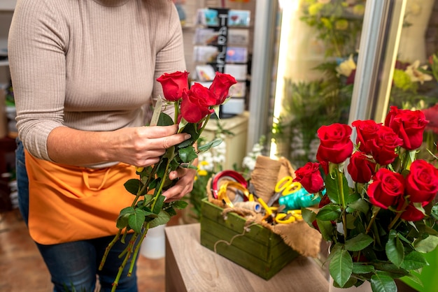 Hände einer Frau, die einen Blumenstrauß auf einem Tisch arrangiert