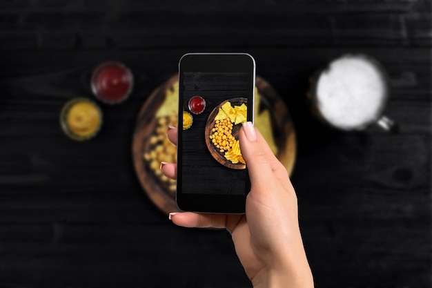 Hände einer Frau, die Foto-Essen mit Handy-Smartphone-Draufsicht macht, mexikanische Nachos mit zwei Ki...