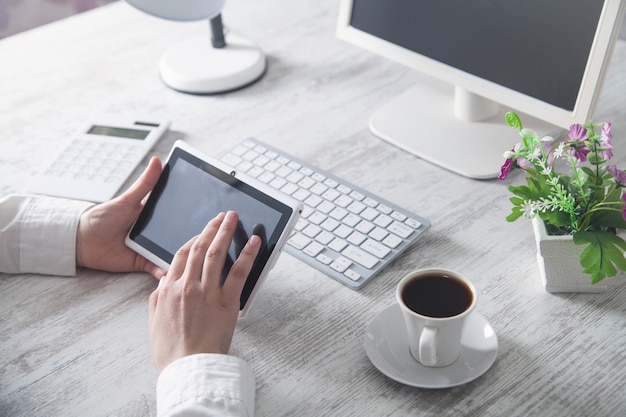 Hände einer Frau, die Tablet-Computer im Schreibtisch verwendet