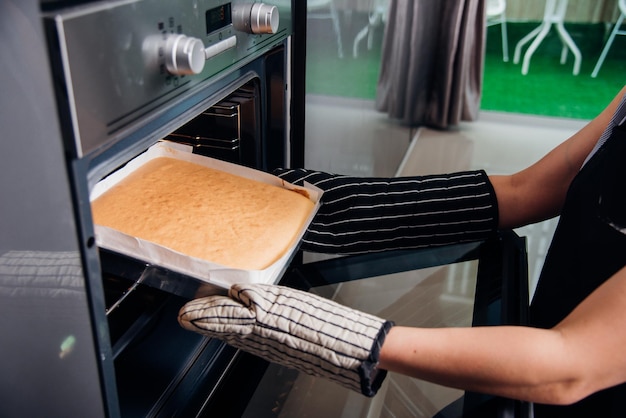 Hände einer Frau, die Teigbrot auf dem vorderen Ofen hält