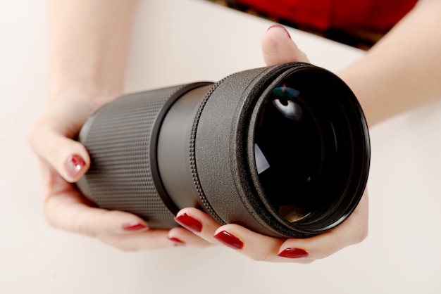 Hände einer Frau mit einem Kameraobjektiv
