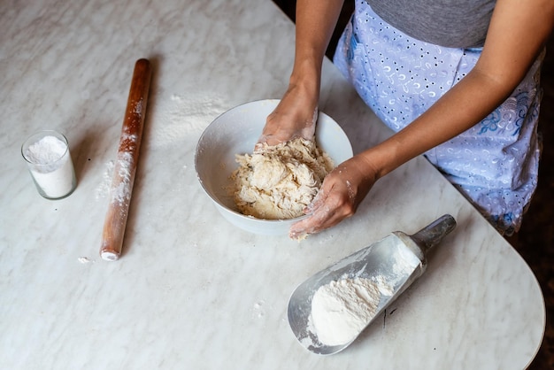 Hände einer jungen Frau, die Teig knetet, um zu Hause Brot oder Pizza zuzubereiten Herstellung von Mehlprodukten Teigherstellung durch weibliche Hände