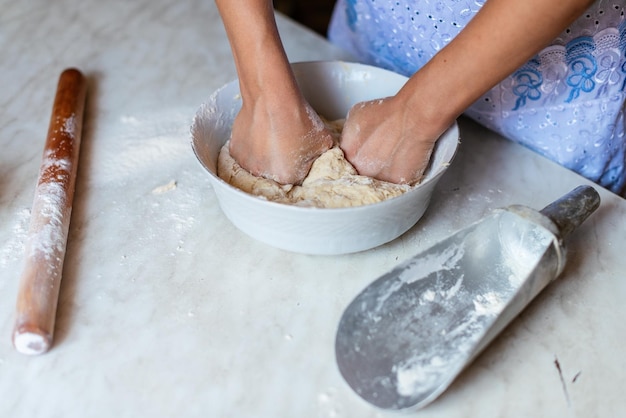 Hände einer jungen Frau, die Teig knetet, um zu Hause Brot oder Pizza zuzubereiten Herstellung von Mehlprodukten Teigherstellung durch weibliche Hände