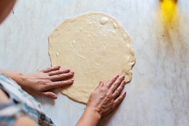 Hände einer jungen Frau, die Teig knetet, um zu Hause Brot oder Pizza zuzubereiten Herstellung von Mehlprodukten Teigherstellung durch weibliche Hände