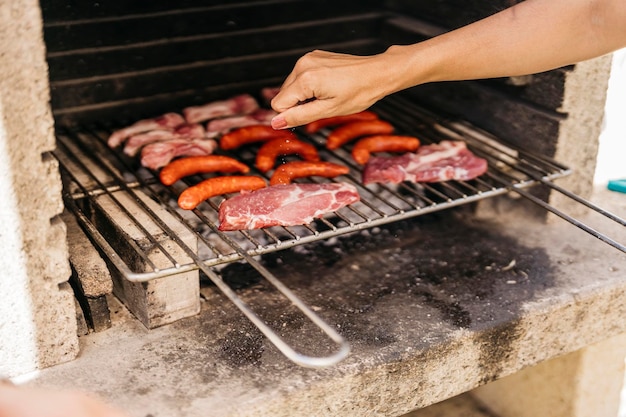 Hände einer jungen lateinischen Frau, die bei einem Grill Salz auf Fleisch reibt