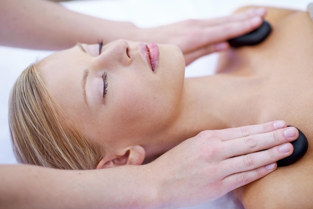 Hände einer Masseurin mit Hot-Stone-Massage im Spa und ganzheitlicher Heilbehandlung mit Zen im Luxus-Wellnessresort Felsen auf Schultern, Frieden mit Therapie und alternativer Medizin zur Selbstpflege