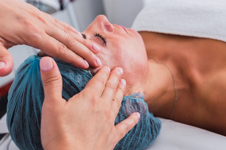 Foto hände einer nicht erkennbaren kosmetikerin, die gesichtsmassage auf dem gesicht einer frau im beauty-spa creme aufträgt.