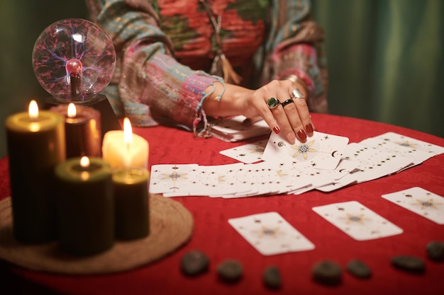 Hände einer Zauberin verteilen Tarotkarten auf dem Tisch vor ihr