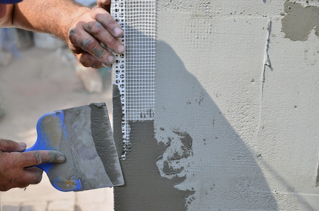 Hände eines alten Arbeiters mit der Wand Werkzeuge vergipsend, die Haus erneuern