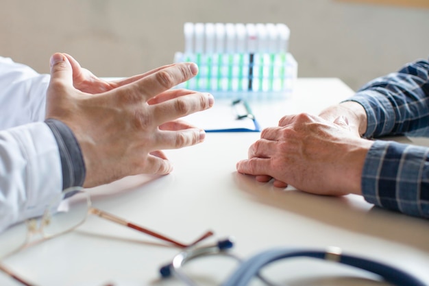 Hände eines Arztes und eines Patienten Nahaufnahme Der Arzt erzählt dem Patienten von seiner Krankheit