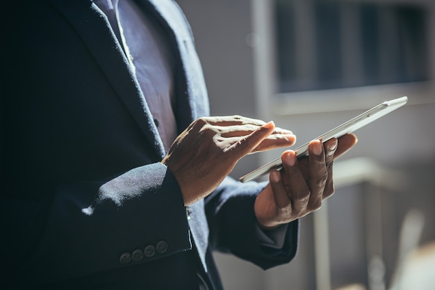 Hände eines Geschäftsmannes in einem Business-Anzug verwenden ein Nahaufnahmefoto eines Tablet-Computers