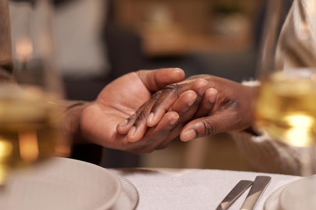 Hände eines jungen afrikanischen Mannes und einer jungen afrikanischen Frau über dem festlichen Tisch während des Gebets vor dem Weihnachtsessen