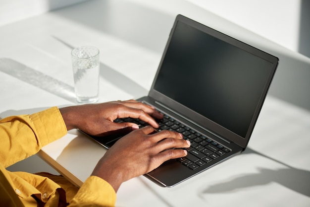 Foto hände eines jungen afroamerikanischen männlichen studenten, der die tasten des laptops berührt