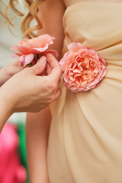 Hände eines jungen Mädchens, das Blumen, Rosen, auf einem Hochzeitskleid korrigiert