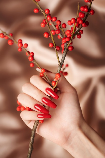 Hände eines jungen Mädchens mit roter Maniküre auf Nägeln