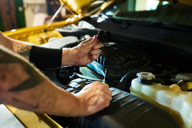 Foto hände eines jungen mannes, der ein detail des automotors über der offenen motorhaube hält