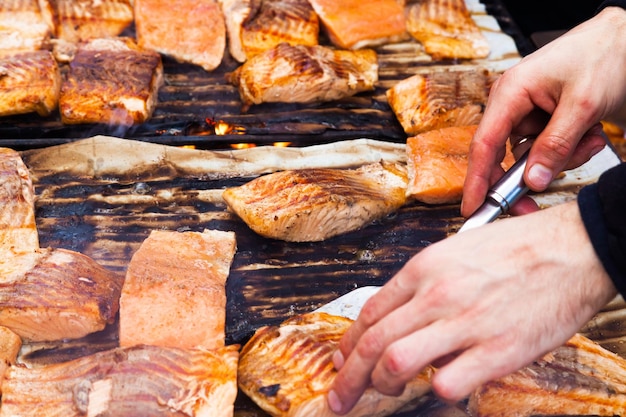 Hände eines Kochs, der roten Fisch auf dem Grill grillt