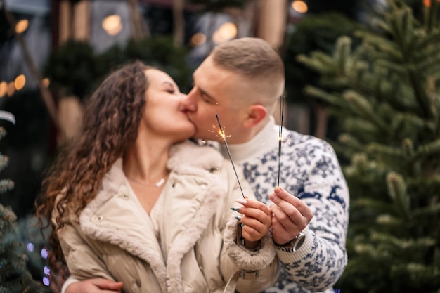 Hände eines Mannes und einer Frau in Nahaufnahme mit einer brennenden Wunderkerze Festliche Lichter