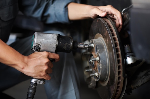 Hände eines Mechanikers, der für den Kunden Autoreifen wechselt