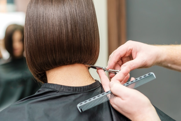 Hände eines professionellen Friseurs, der Haare schneidet